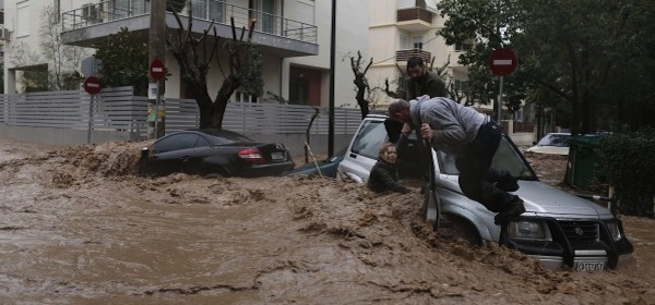 A woman is rescued from flood waters by a resident standing on her car during heavy rain in Halandri, north of Athens.