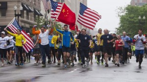 Runners carry American flags and Chinese flag as they approach finish line after completing final mile of the Boston Marathon course during "#onerun" in Boston