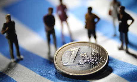 Figurines and a euro on a Greek flag