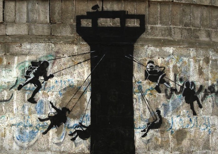 Children swinging from an Israeli watch tower by Banksy, Photo via banksy.co.uk