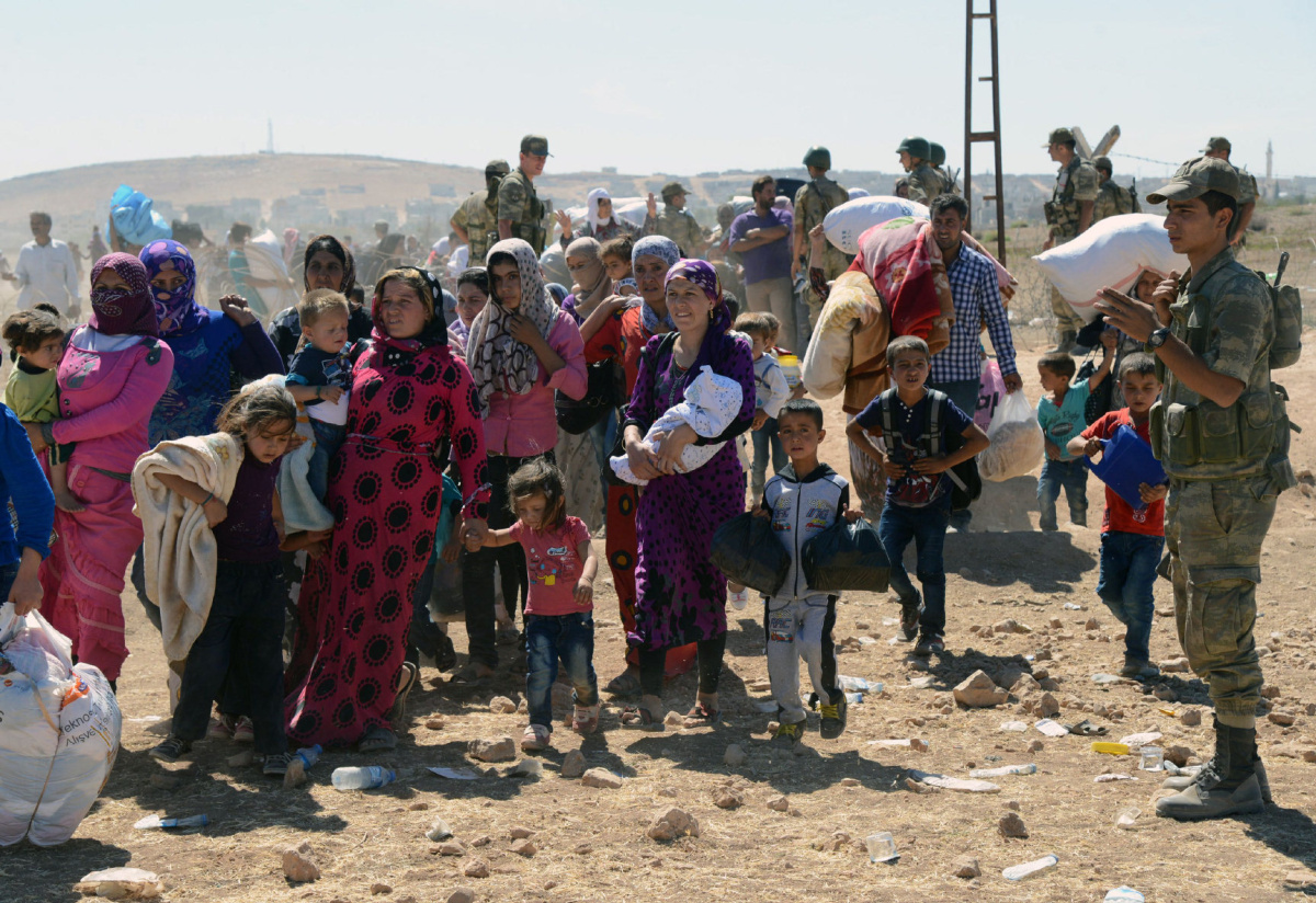 Syrian refugees gather at the border in Suruc, Turkey, Saturday, Sept. 20, 2014. Several thousand Syrians, most of them Kurds, crossed into Turkey on Friday to find refuge from Islamic State militants who have barreled through dozens of Kurdish villages in northern Syria in the past 48 hours. (AP Photo)
