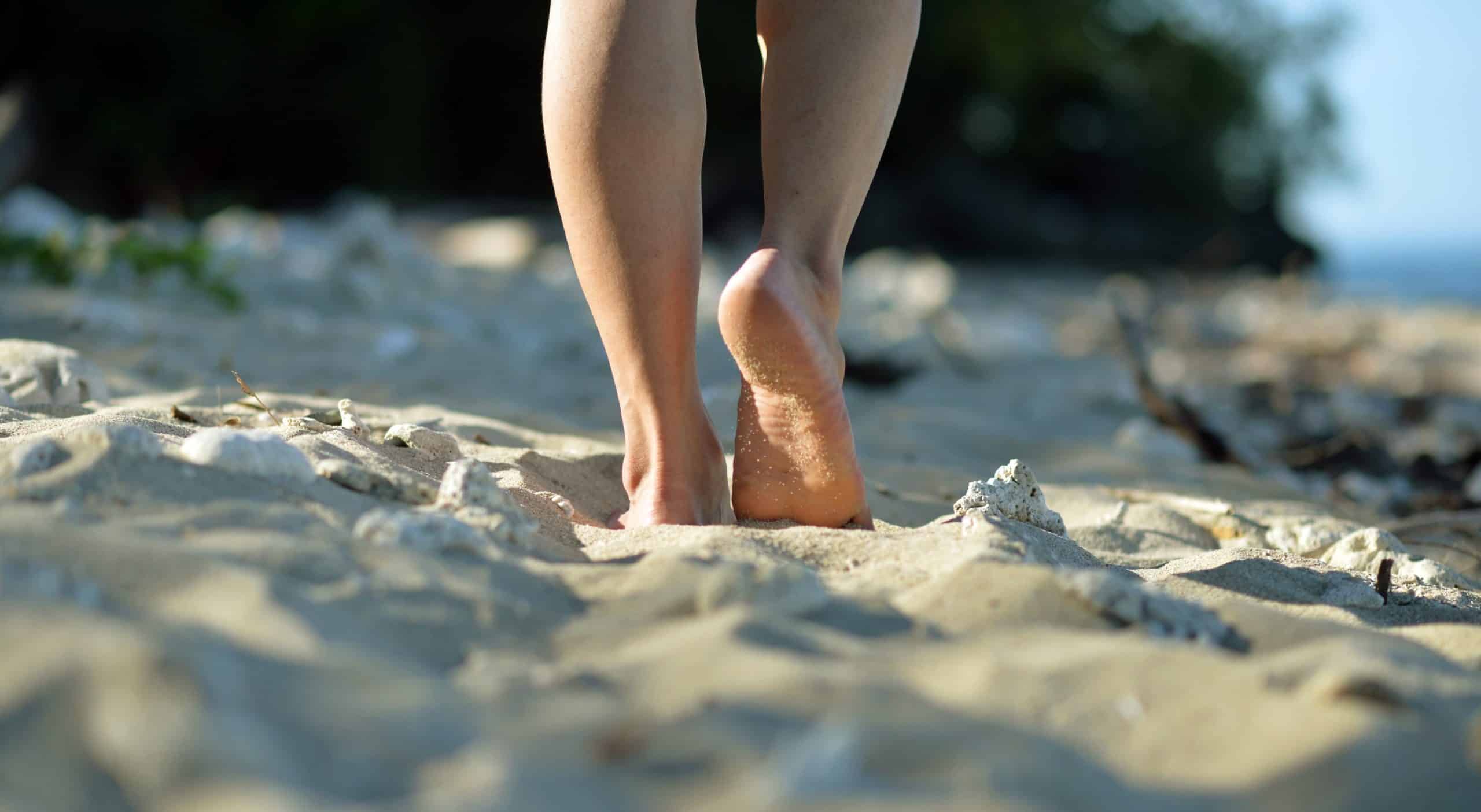 woman walking barefoot on sand 