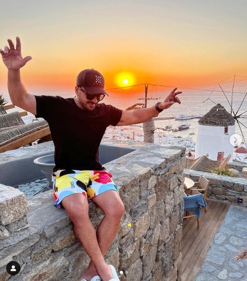 Luis Fonsi posing for a photo with the white windmills of Mykonos in the background. 