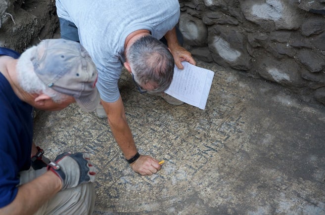 Archaeologists cleaning an ancient Greek inscription at el Araj site in Israel.