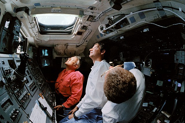 Crew members looking out of the overhead windows at the Hubble Space Telescope