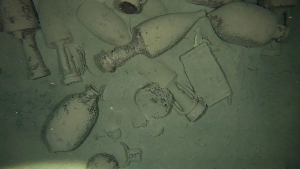 Scattered ceramics on the seafloor, remnants from an ancient Roman shipwreck.