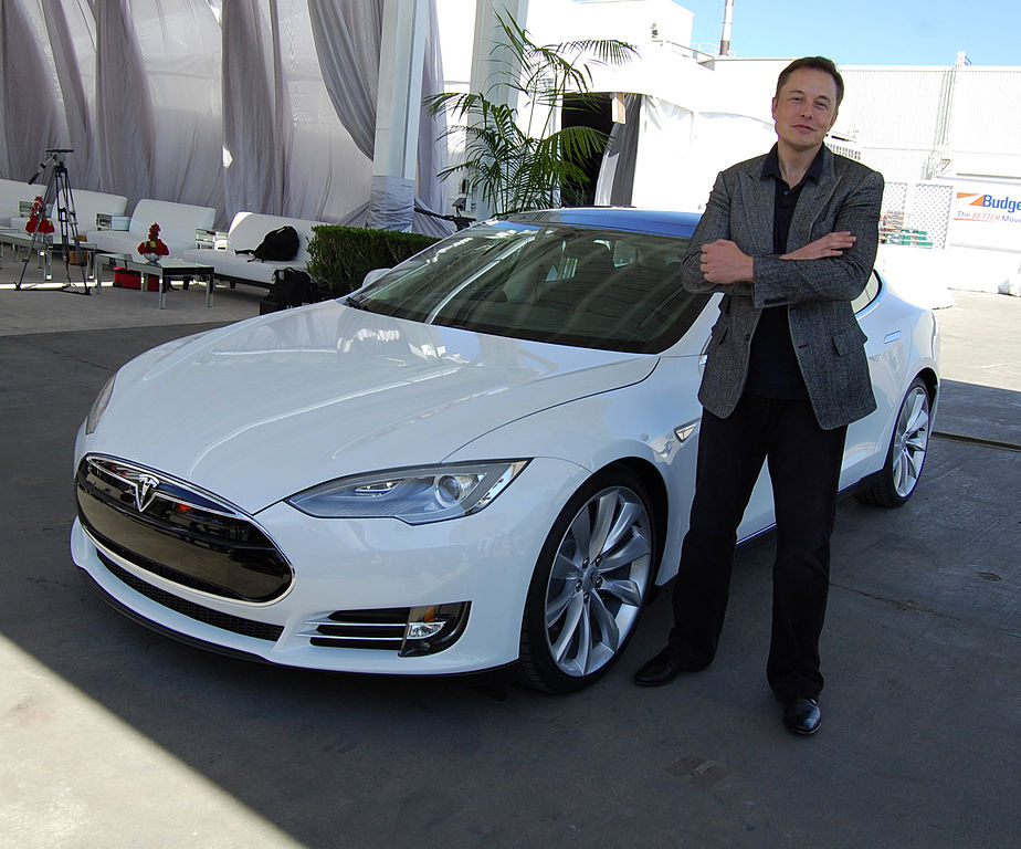 Tesla CEO Elon Musk in front of a white Tesla car