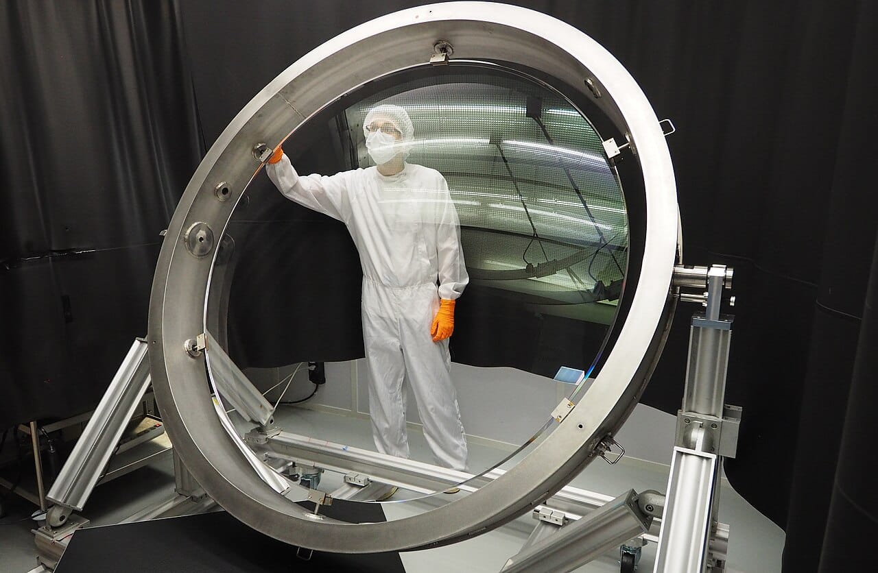 A technician seen through the human-sized L1 lens of the Rubin Observatory camera