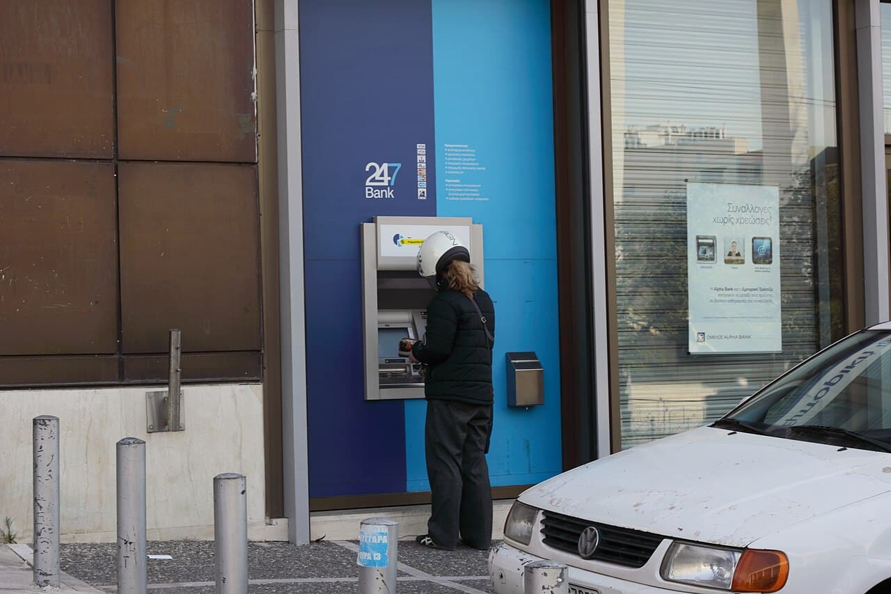 An individual uses an ATM in Greece