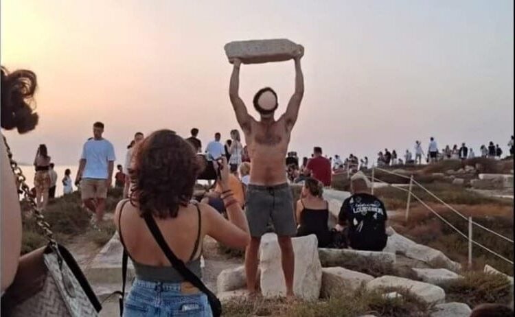 Tourist lifts ancient marble at Portara on Naxos
