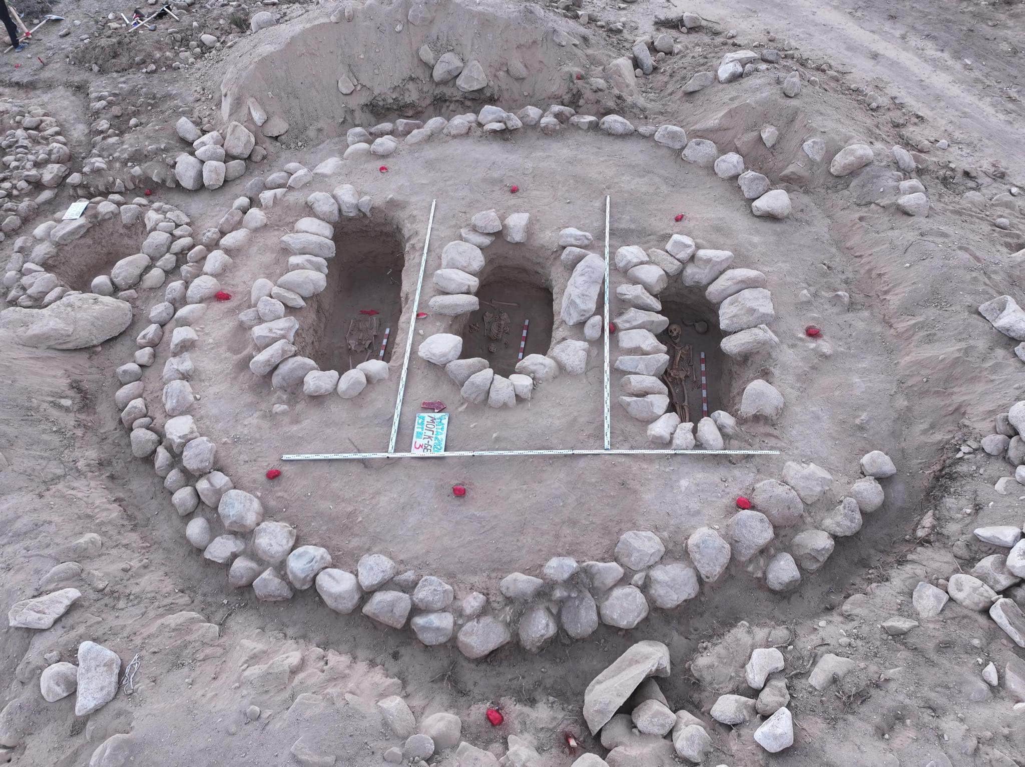 Exposed graves within a circular stone enclosure in the Issyk-Kul region