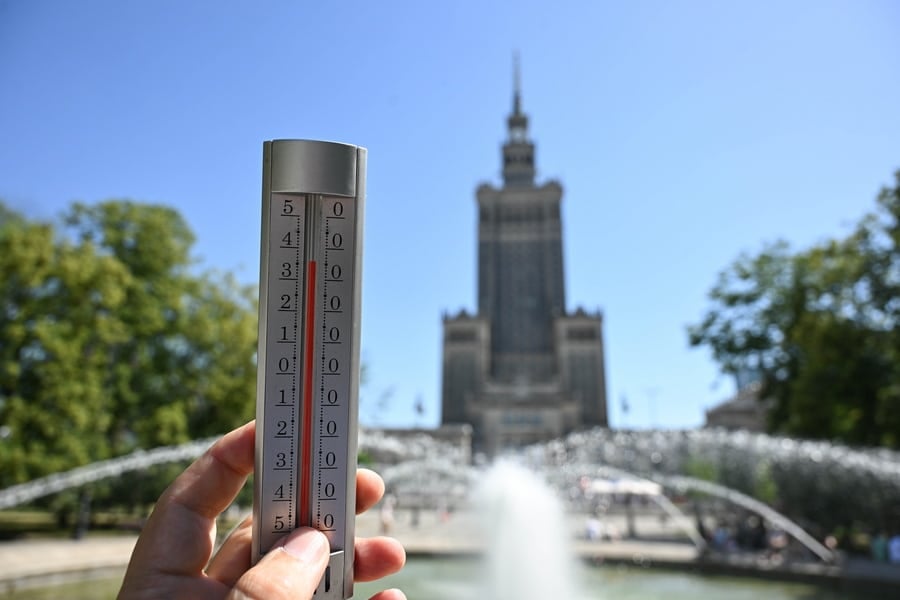 Thermometer reading in front of Krakow landmark building during heatwave