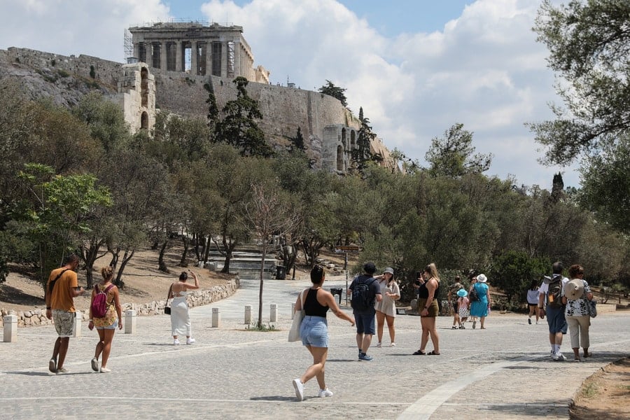Tourists walk near the Acropolis in Athens, Greece, as the Parthenon is seen in the background.