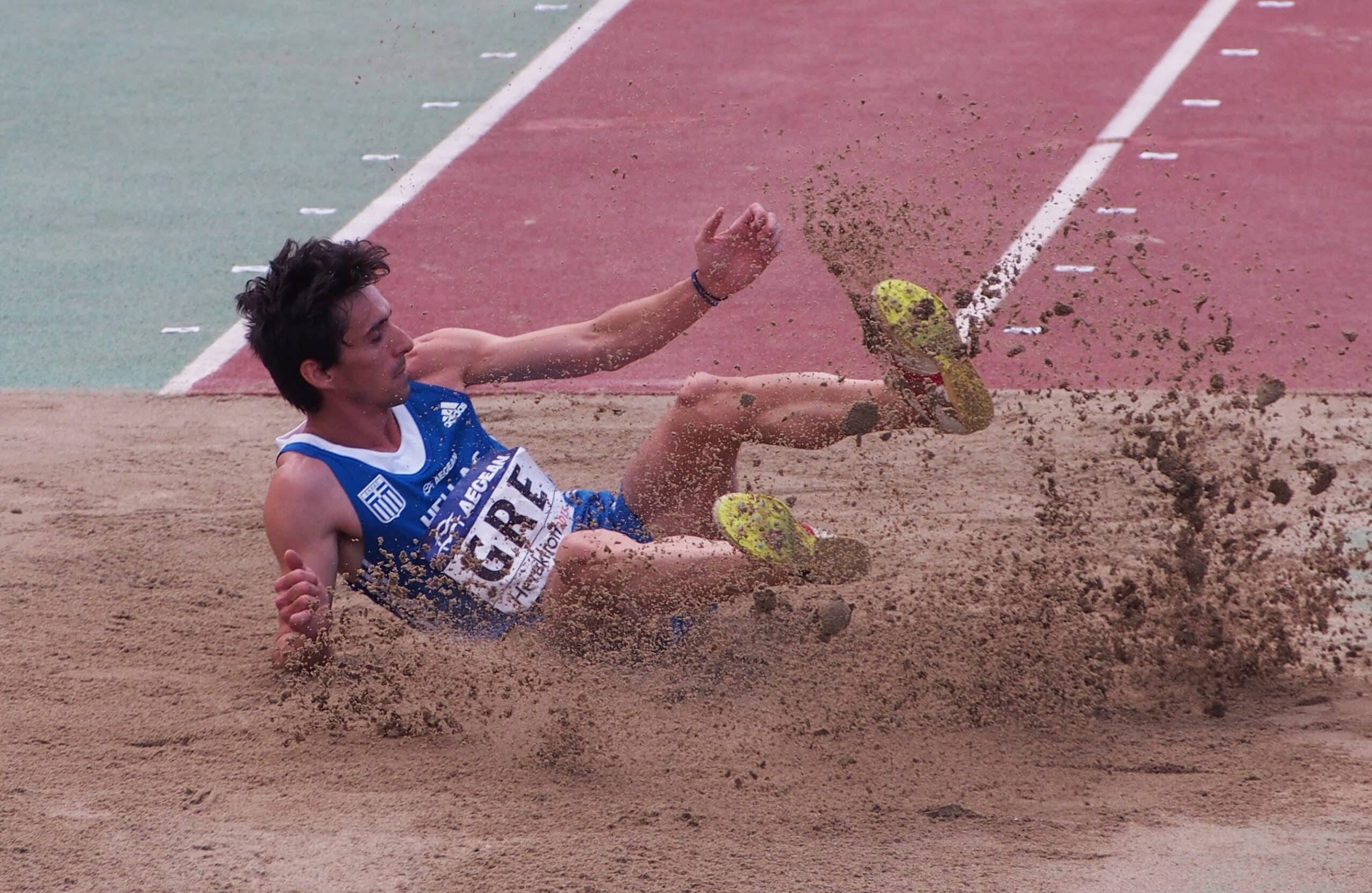 Greek triple jumper Dimitris Tsiamis lands in the sand pit during a track and field competition.