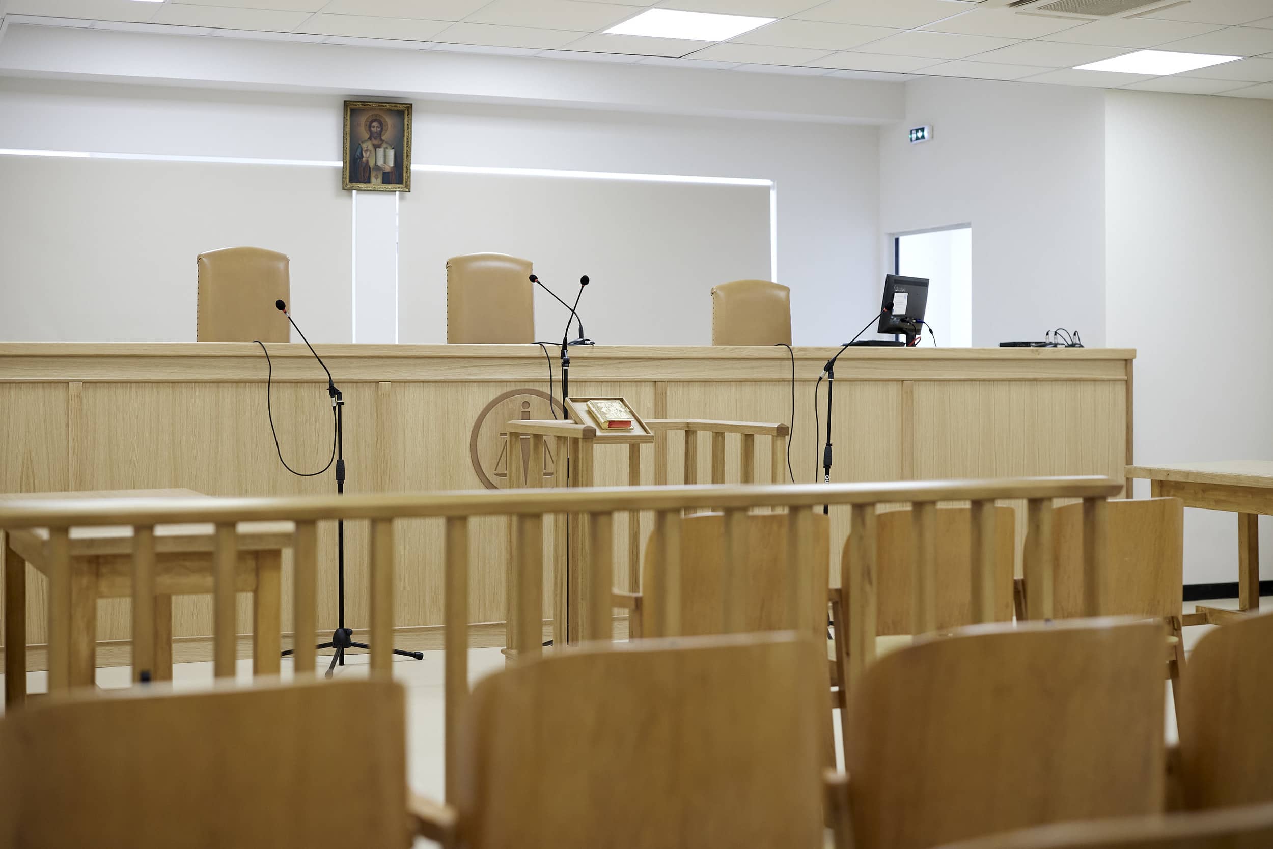 Empty court room in Greece with judges’ chairs, microphones, and wooden benches. A Greek court in Aigio sentenced James Dalamangas after his arrest in the Peloponnese following a nearly 27-year manhunt over Sydney killing.