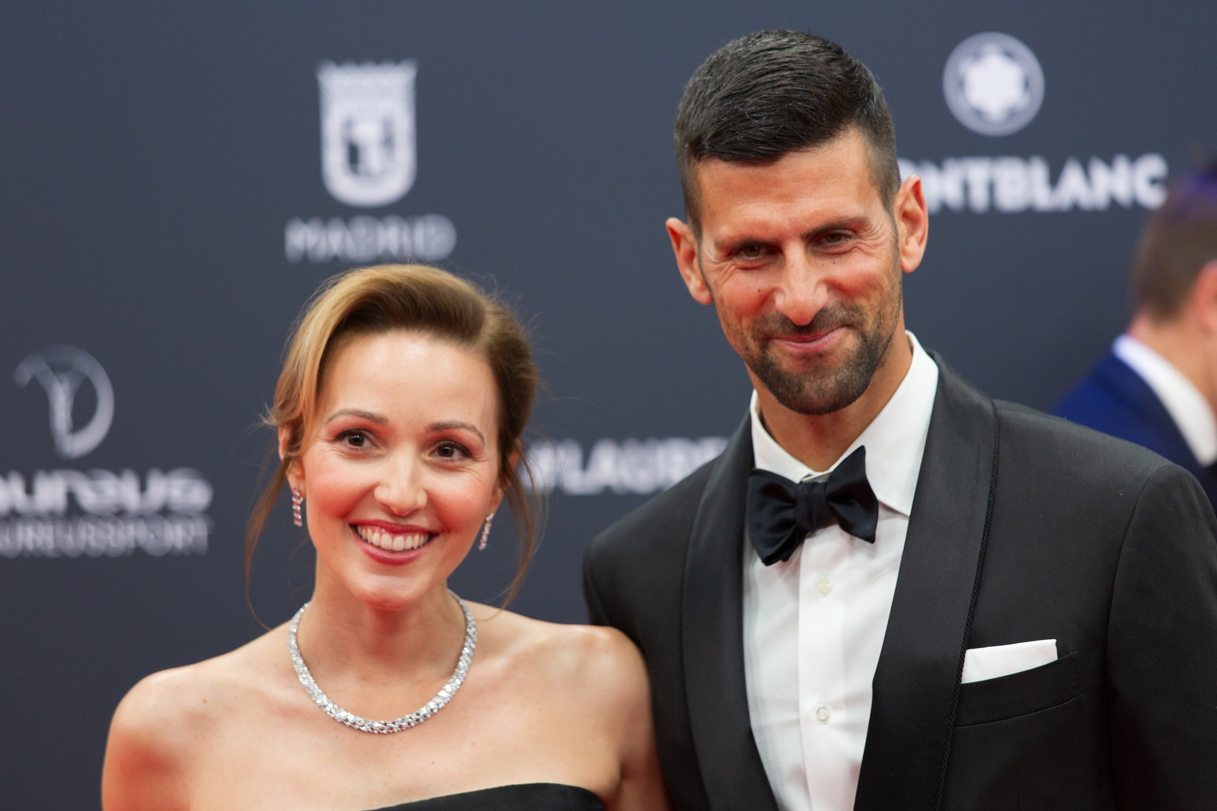 Novak Djokovic and Jelena Djokovic smiling together at a formal red-carpet event.