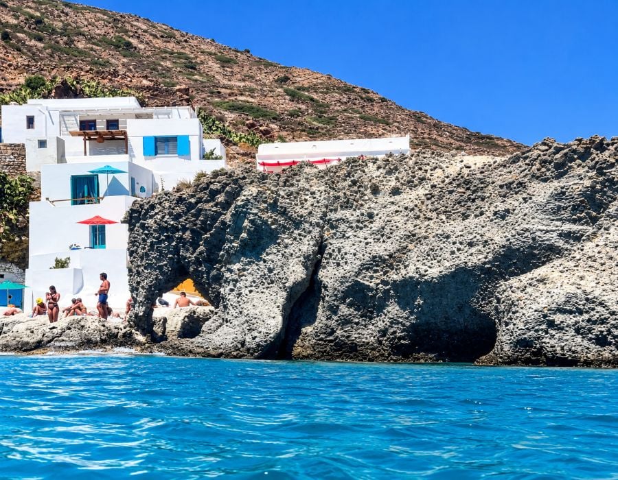 The unusual rocky landscape of Kimolos rises behind the clear waters of the Aegean