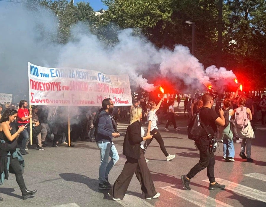 Students take part in a protest rally in Athens as red flares illuminate the crowd amid smoke on October 21, 2026.