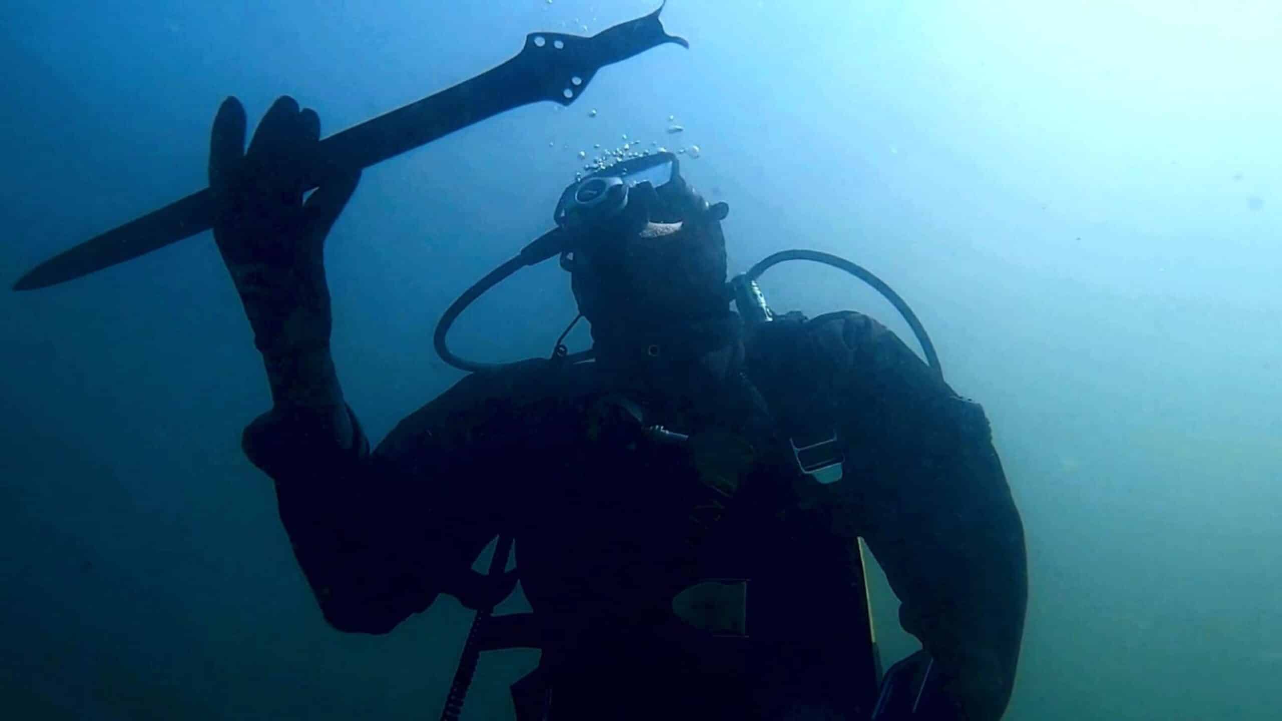 An underwater archaeologist holds the 3,000-year-old bronze sword recovered from Lake Mezzano in central Italy