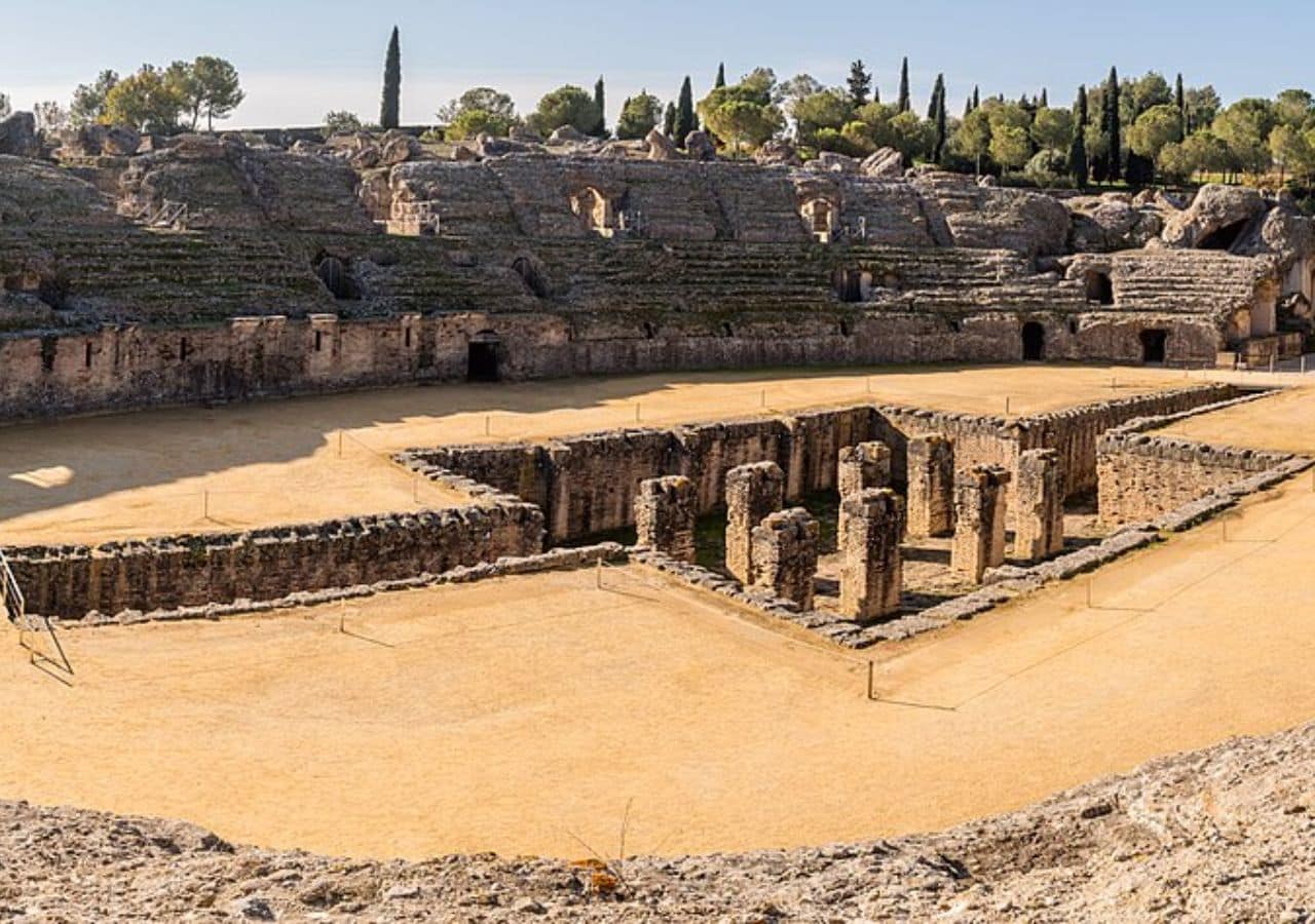 The surviving arena and curved seating of the ancient Roman amphitheater at Italica near Seville, Spain