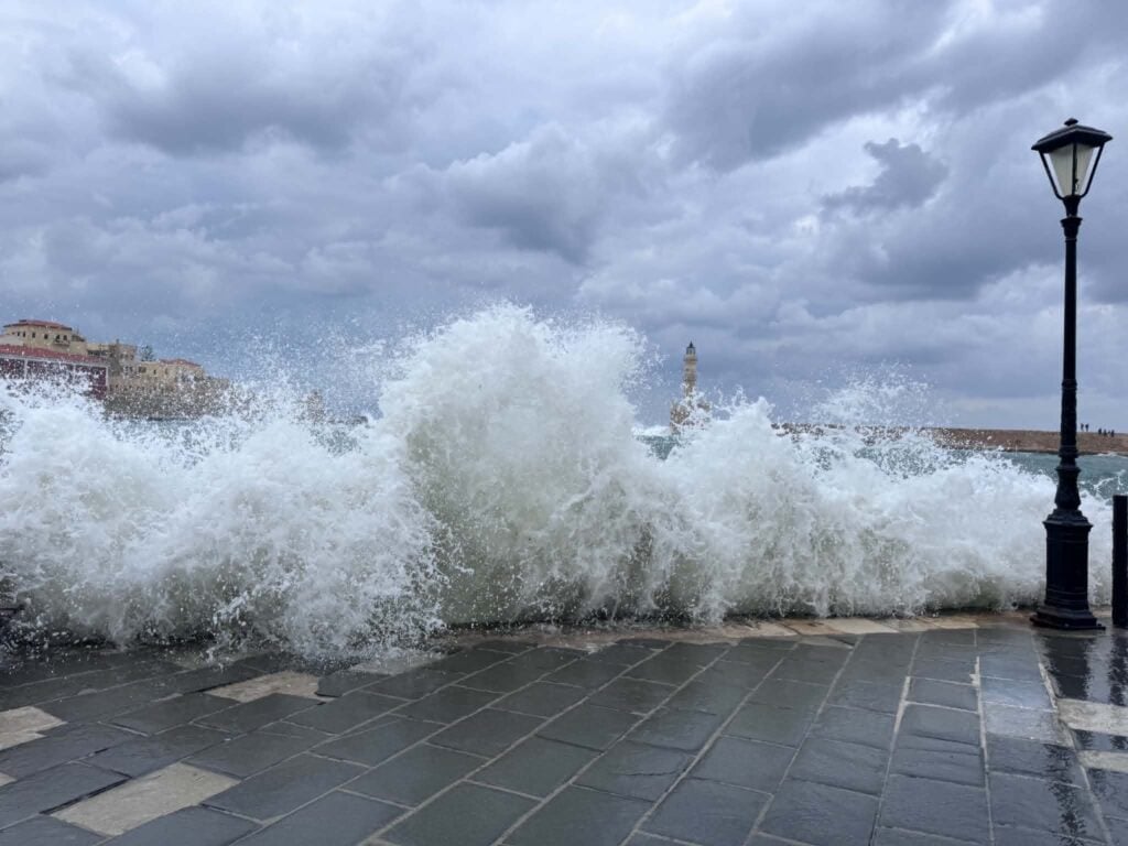 Powerful waves crash over a coastal promenade as severe storms bring flooding and travel disruptions across Greece.