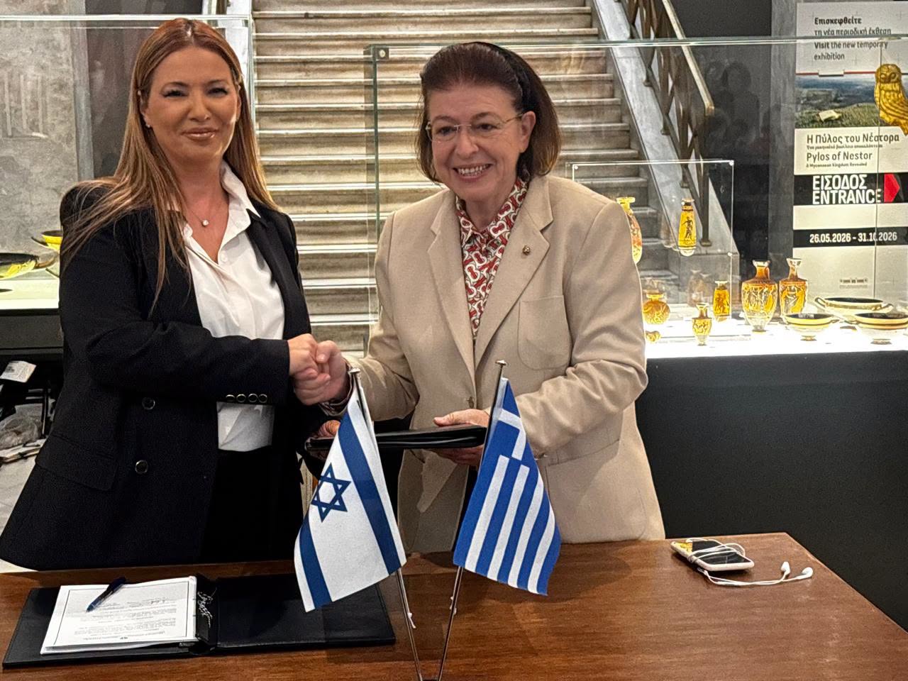 Greek Culture Minister Lina Mendoni (right) shakes hands with Israel's Ambassador to Greece, Pninat Yanay, during a handover ceremony at the National Archaeological Museum in Athens on October 13, 2026. Israel returned 22 antiquities illegally removed from Greece, marking the first repatriation of Greek antiquities from Israel. (Photo: Greek Ministry of Culture)