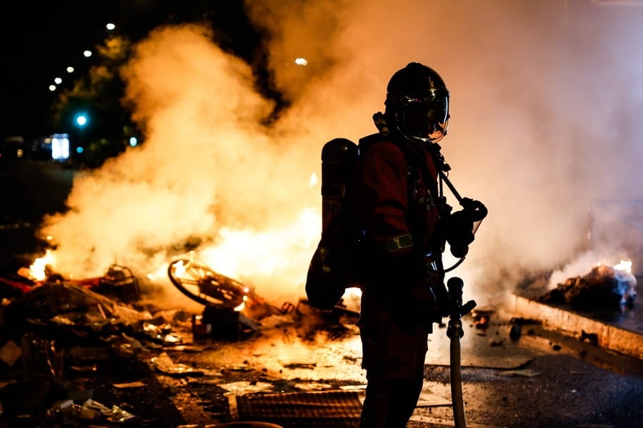 A firefighter in Paris responds to a street barricade burns as clashes between riot police and demonstrators continue for the second day in France.