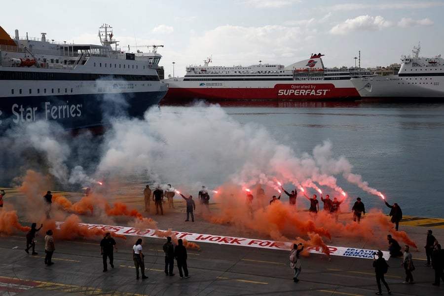 Members of Greek maritime unions hold flares during an anti-war protest at the port of Piraeus, Greece, on October 30, 2026, under the slogan “Dockworkers don’t work for war.” Credit: AMNA/Yannis Kolesidis.